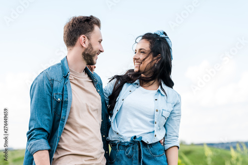cheerful and attractive girl smiling while looking at handsome man