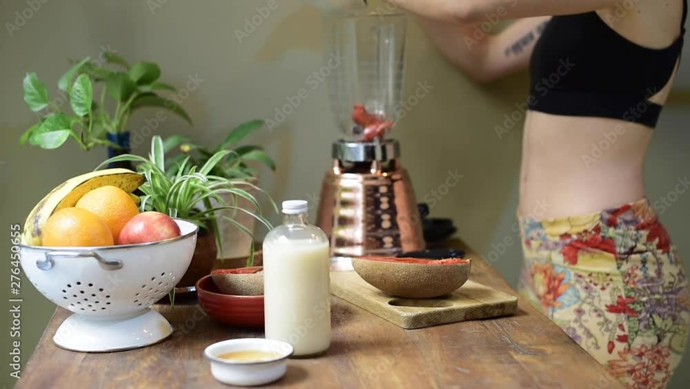 mujer joven preparando un batido licuado de fruta desayuno saludable
