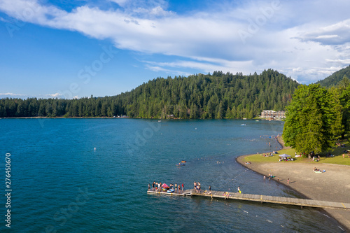 Aerial photo of Cultus Lake in Chilliwack, B.C. while people are enjoying the summer activities at the lakeshore and doing barbeque in the woods by the lake