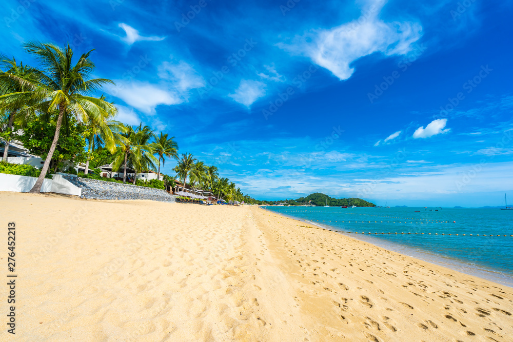 Beautiful tropical beach sea and ocean with coconut palm tree and umbrella and chair on blue sky and white cloud Beautiful tropical beach sea and ocean with coconut palm tree and umbrella and chair on blue sky and white cloud