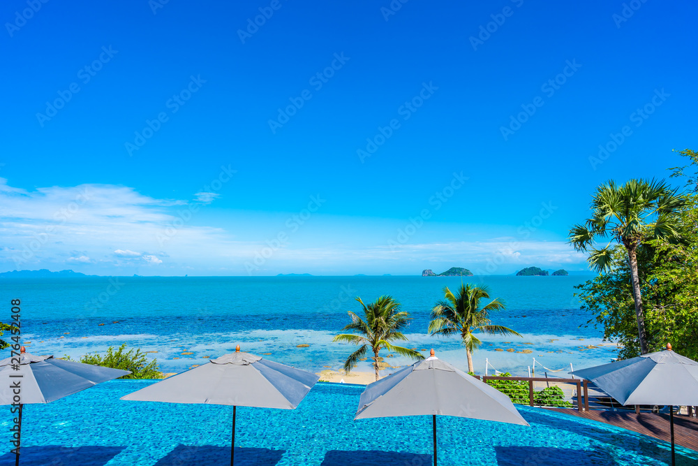 Naklejka premium Beautiful luxury outdoor swimming pool in hotel resort with sea ocean around coconut palm tree and white cloud on blue sky