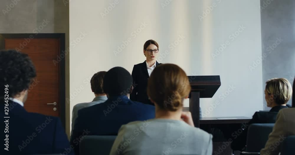 Young Caucasian female professor having a lection to the audience, interacting and communicating with people and giving a word to someone from the audience. Young Caucasian female professor having a lection to the audience, interacting and communicating with people and giving a word to someone from the audience.