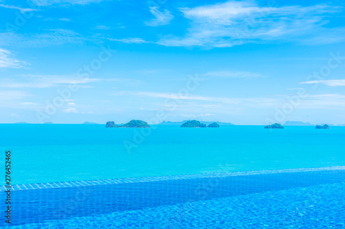 Beautiful luxury outdoor infinity swimming pool with tropical sea ocean and white cloud blue sky background