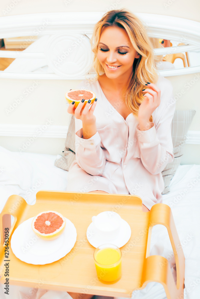 young beauty blond woman having breakfast in bed early sunny morning, princess house interior room, healthy lifestyle concept
