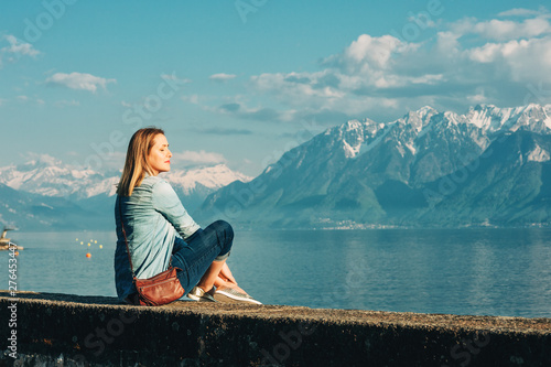 Outdoor portrait of happy young woman relaxing by the lake on a nice sunny day, peacful and harmonious mood