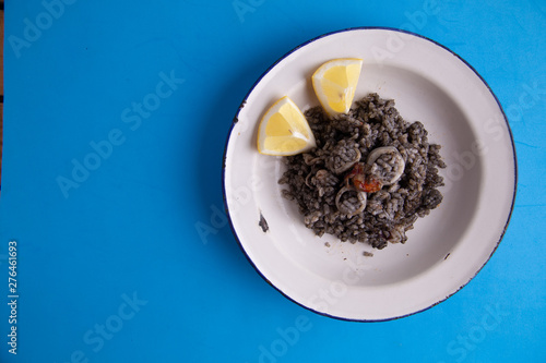Plate of black rice with squid and prawns or Valencian black paella