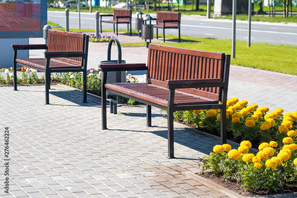 Wooden bench for rest and garbage bin in a city park.