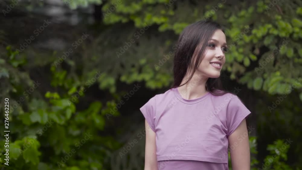 Young attractive woman is slowly dancing in solo in front of a green trees. Woman has very smooth movements. She is posing for the photos. Young attractive woman is slowly dancing in solo in front of a green trees. Woman has very smooth movements. She is posing for the photos.