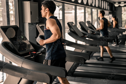 man in sportswear running on treadmill at gym