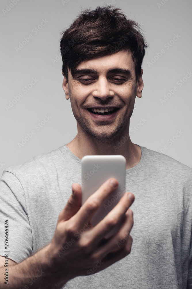 cheerful man having video call on smartphone isolated on grey