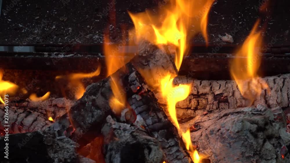 Flames from burning firewood from fruit trees on an open grill