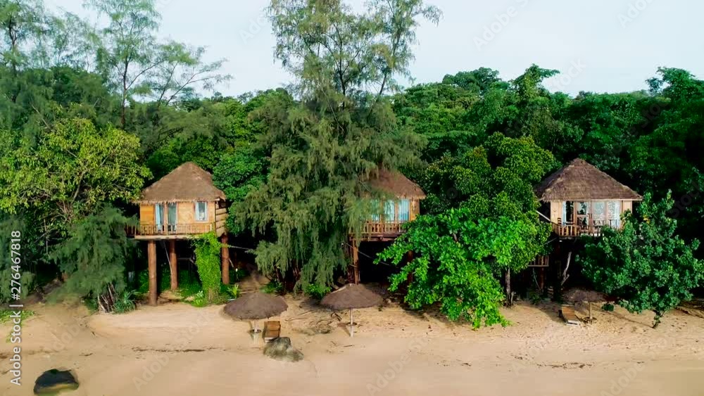 Aerial view of wild beach with white sand, cottages, straw huts, bungalows. Forest and mountain in background. Koh Rong Smaller, Cambodia. Royalty high quality stock footage. flying along coastline. Aerial view of wild beach with white sand, cottages, straw huts, bungalows. Forest and mountain in background. Koh Rong Smaller, Cambodia. Royalty high quality stock footage. flying along coastline.
