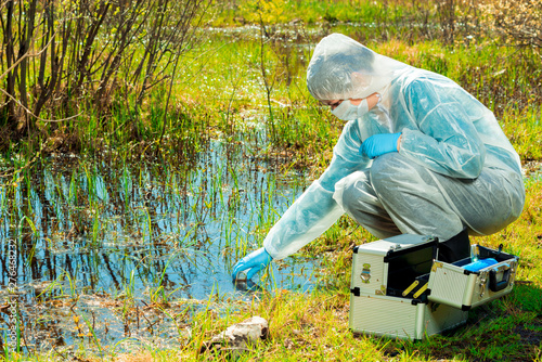 experienced ecologist on the shore of a forest lake takes water samples © kosmos111