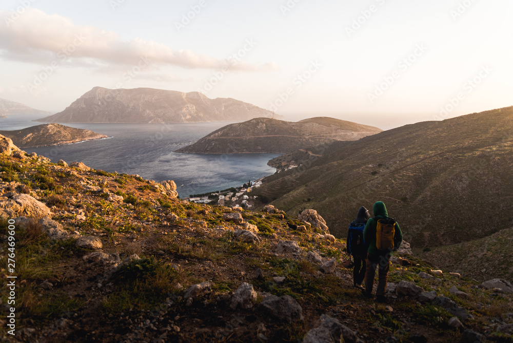 Two people hiking down a hill during sunset in Kalymnos, Greece. 