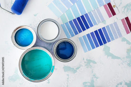 Cans of paint with palette samples on light background photo