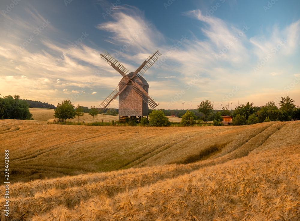 Fototapeta premium wooden windmill on a summer field during sunset