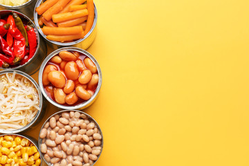 Tin cans with different food on color background