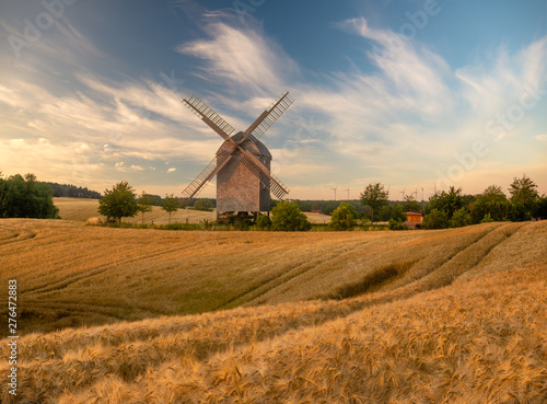 wooden windmill on a summer field during sunset