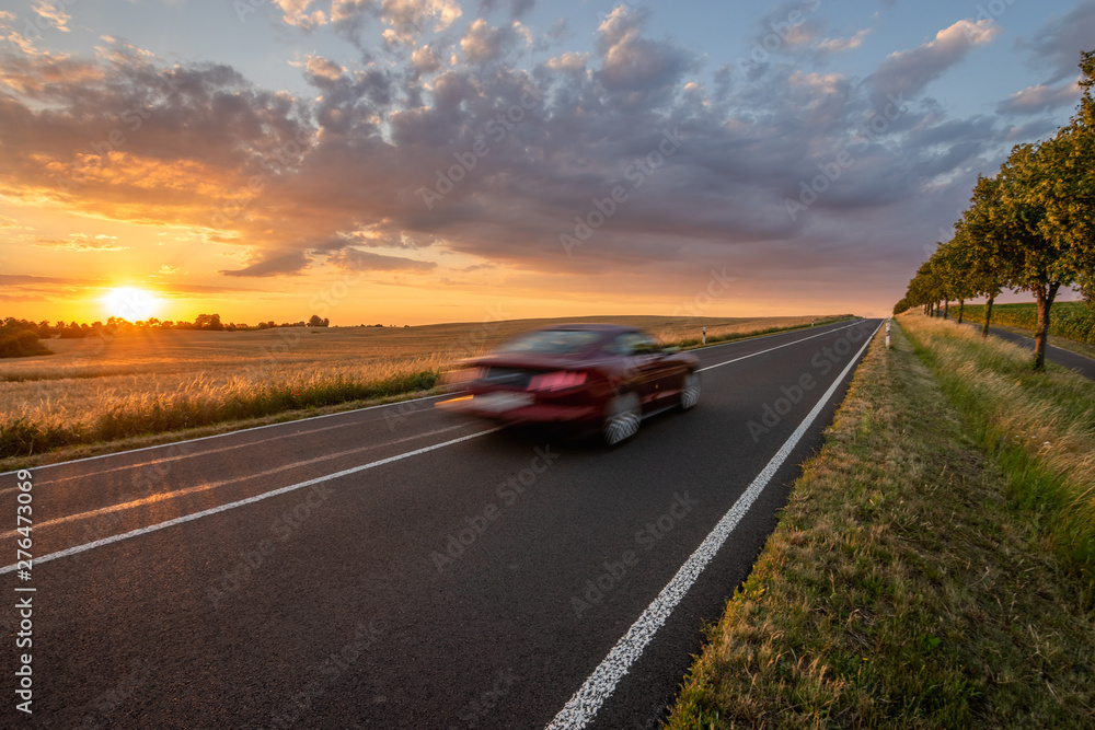 sports car driving an asphalt road in Germany during a beautiful summer sunset