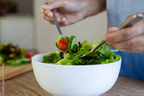 Asian woman mixing fresh vegetable salad ingredients in the kitchen