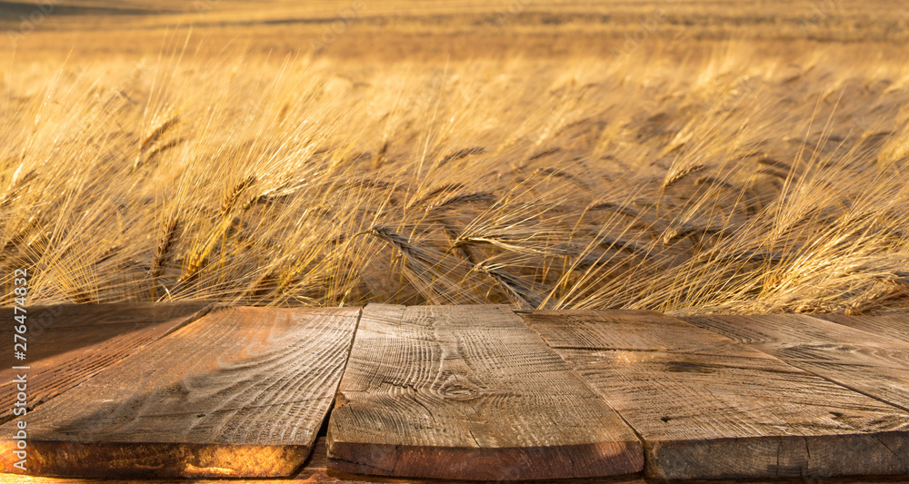wood board table in front of field of wheat - obrazy, fototapety, plakaty 