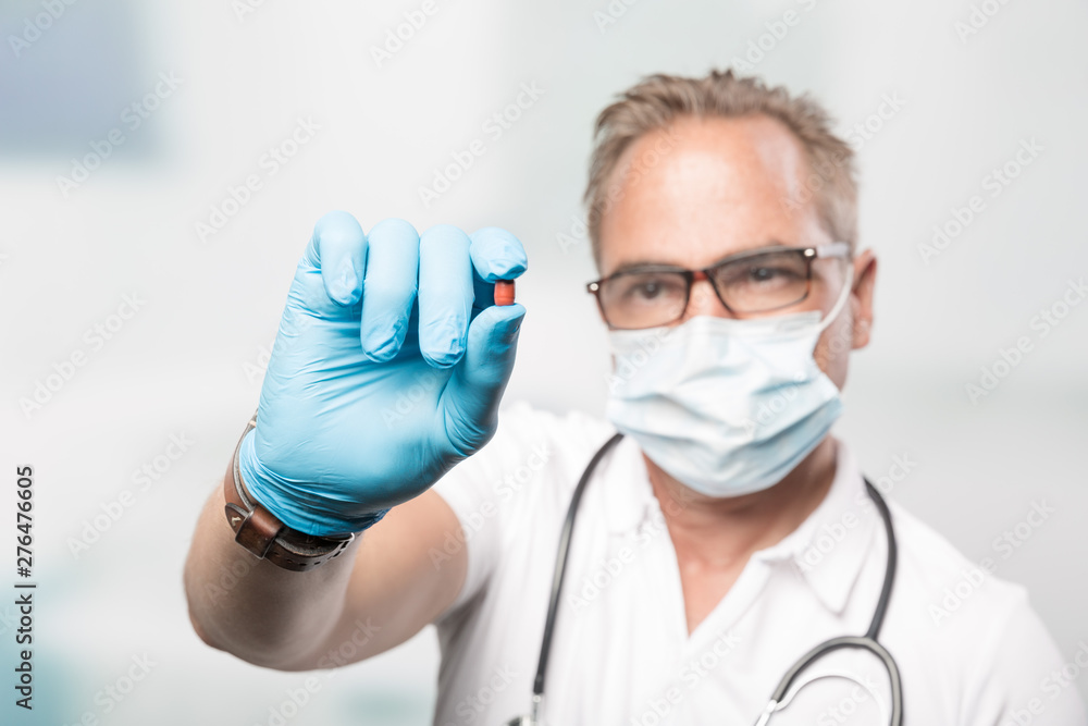 Pharma Scientist or doctor with medical face mask and gloves shows a medicin pill in his hand Pharma Scientist or doctor with medical face mask and gloves shows a medicin pill in his hand