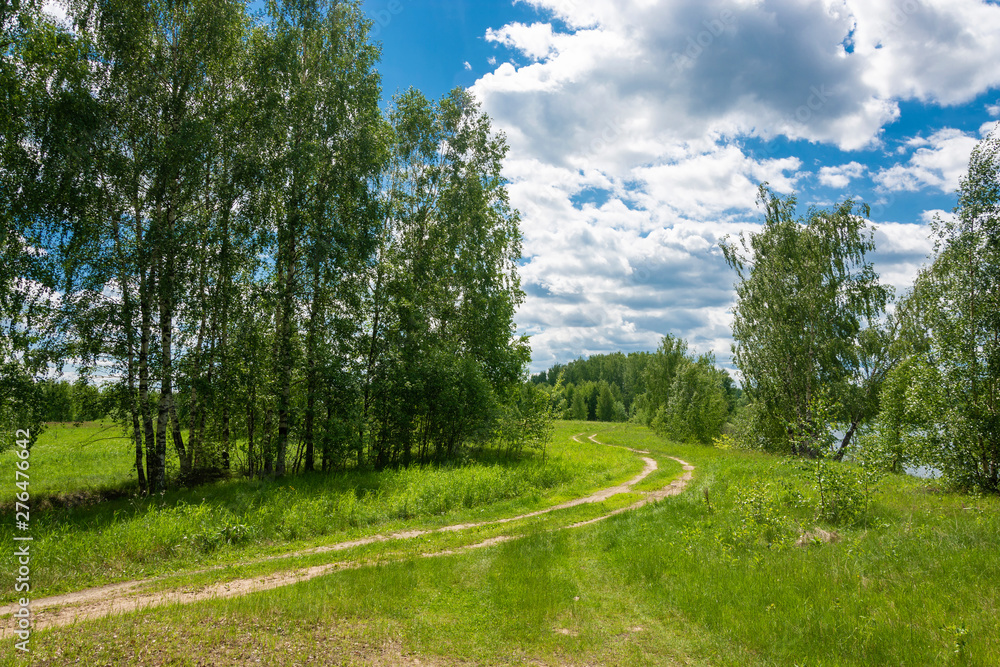 A winding dirt road by the river on a sunny summer day. A winding dirt road by the river on a sunny summer day.
