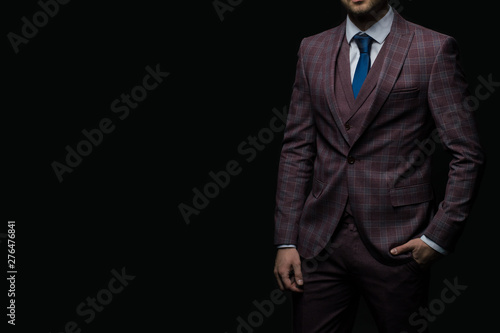 Young handsome successful and confident bearded business man in a suit. Isolated on dark background, copy space.