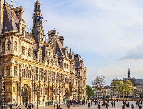 Paris / France - April 04 2019: Square in front of Hotel de Ville, the Municipality of Paris, full of resting people at sunset. View on Notre Dame Cathedral before fire