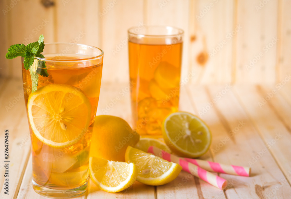Glasses of ice tea with lemon slices and mint on wooden background