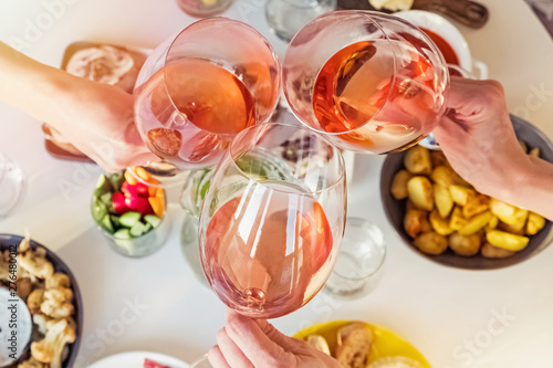 Fototapeta Naklejka Na Ścianę i Meble -  Hands holding glasses with rose wine over the table with food.