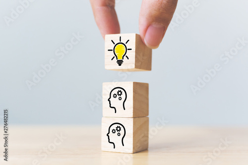 Concept creative idea and innovation. Hand picked wooden cube block with head human symbol and light bulb icon