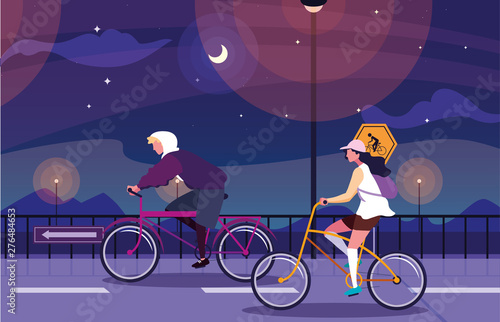 couple riding bike in night landscape with signage for cyclist