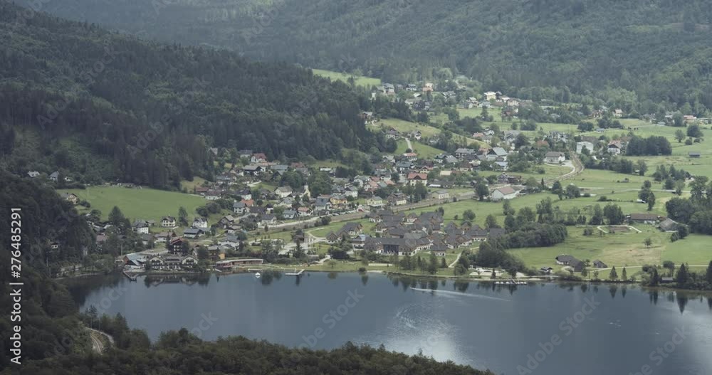 Landscape panorama of the valley where the small Austrian city Hallstatt Obertraun is located with the green fields and forests all around and the natural lake in front.