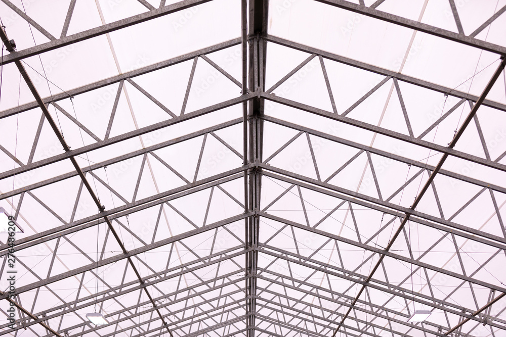 View at a horse riding arena roof with metal frames and a plastic stretched across it View at a horse riding arena roof with metal frames and a plastic stretched across it