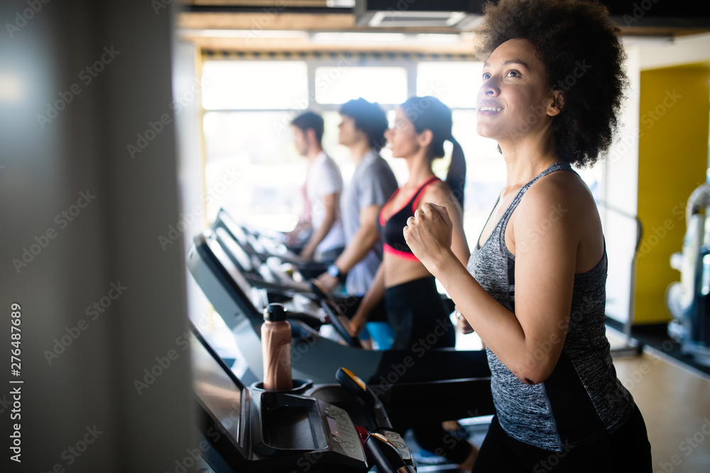 Fototapeta premium Młodzi ludzie biegający na bieżni w klubie fitness.