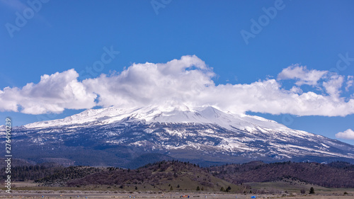 Mount Shasta, California with clouds on a sunny day against bright blue sun from I-5 interstate © Dmitry