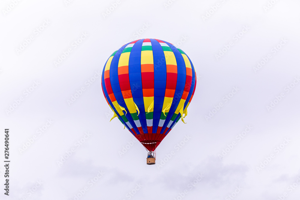 Fototapeta premium Woodburn, Oregon \ USA - 21 April 2019: A hot air balloon with blue, yellow and red stripes taking passengers into the sky