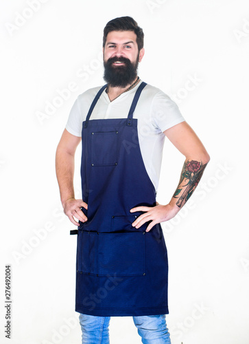 Casual and stylish. Happy cook wearing cooking apron with pockets. Cook in apron keeping hands on hips. Bearded cook happy smiling in kitchen apron. Confident grill cook with long beard and mustache