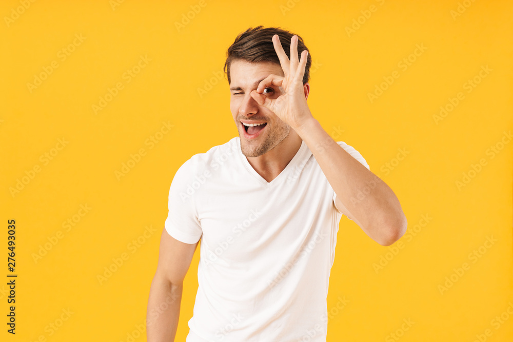 Photo of cheery man in basic t-shirt smiling at camera while showing ok sign Photo of cheery man in basic t-shirt smiling at camera while showing ok sign