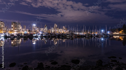 Vancouver, BC \ Canada - 13 March 2019: A night long exposure photo of marina inside Burrard Inlet of Vancouver Harbor with many yachts and boats against colorful illuminated city skyline
