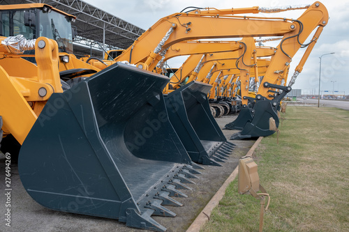 Lots of yellow tractors or excavators at an exhibition