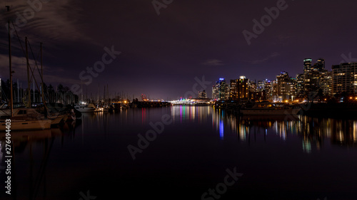 Vancouver  BC   Canada - 13 March 2019  A night long exposure photo of marina inside Burrard Inlet of Vancouver Harbor with many yachts and boats. Lights of Canada place are in the background
