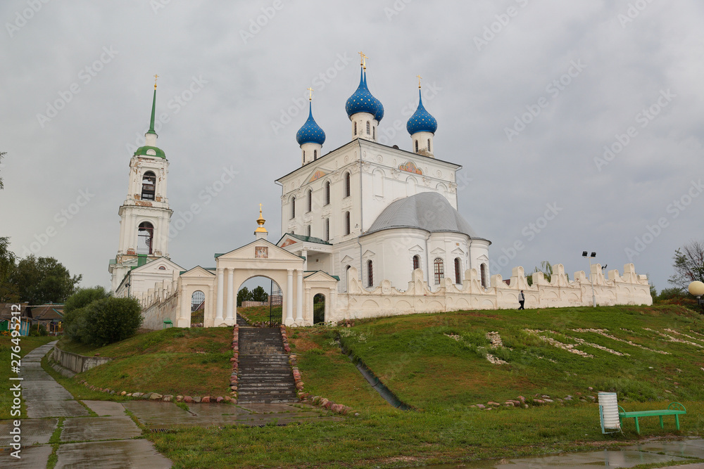 Katunki \ Russia - 03 August 2016: View at a Church of the Nativity of the Blessed Virgin. White tall church with 5  blue domes and a bell tower