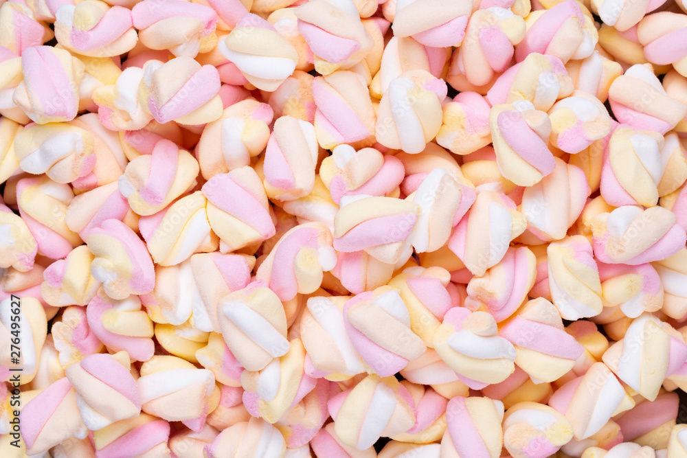 Fototapeta premium Marshmallows on blue background with copyspace. Flat lay or top view. Background or texture of colorful mini marshmallows.