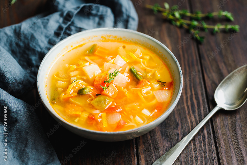 Spring vegetable soup with chicken stock for one person on wooden table. Rustic style, close-up view. Spring vegetable soup with chicken stock for one person on wooden table. Rustic style, close-up view.