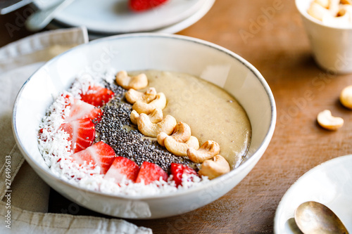 Smoothie bowl with banana, matcha, coconut cream, strawberry, cashew and chia seeds. Healthy vegan eating.