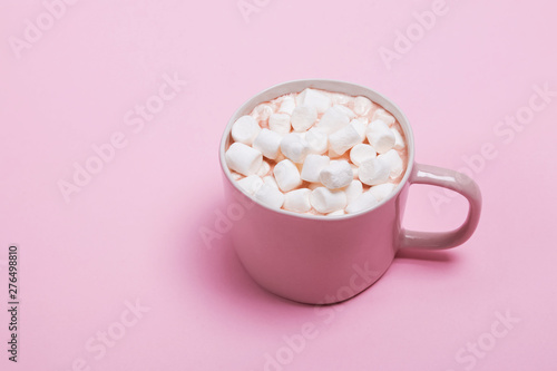 A cup of hot cocoa with a lot of marshmallows on the pink background