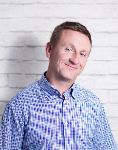 Smiling middle aged man on white brick wall background