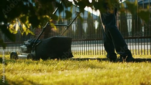 Man cutting grass with a full bag lawn mower in the backyard
